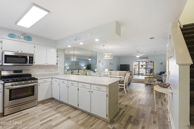 kitchen with a peninsula, ceiling fan, stainless steel appliances, light countertops, and open floor plan