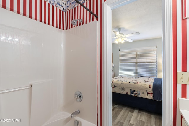 bathroom with wood finished floors, ceiling fan, and shower / bathtub combination