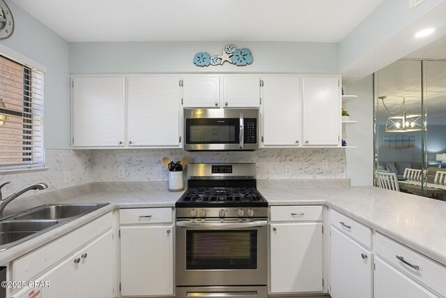 kitchen with ceiling fan, backsplash, kitchen peninsula, white cabinetry, and stainless steel appliances