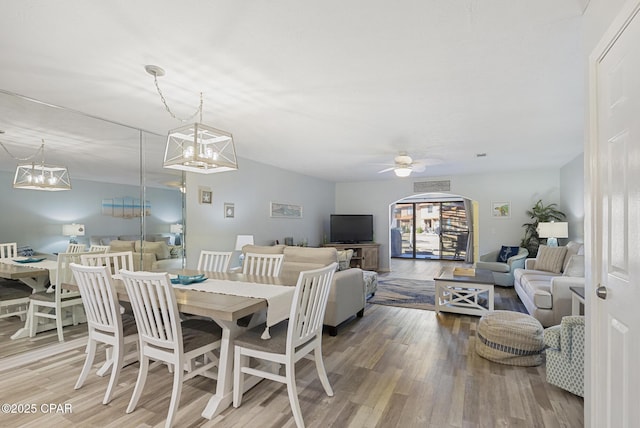 dining area featuring ceiling fan with notable chandelier and wood finished floors