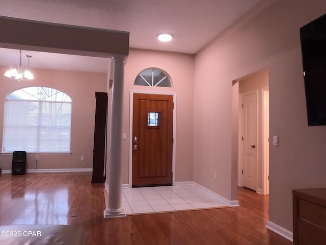 foyer with light wood-type flooring, decorative columns, and a chandelier