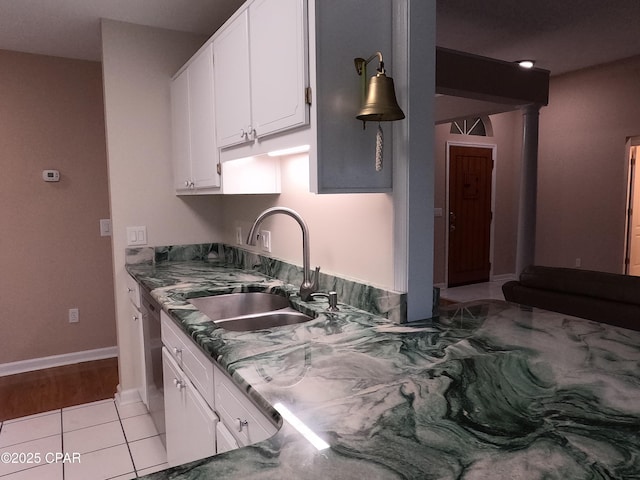 kitchen featuring white cabinets, dishwasher, light tile patterned flooring, and sink