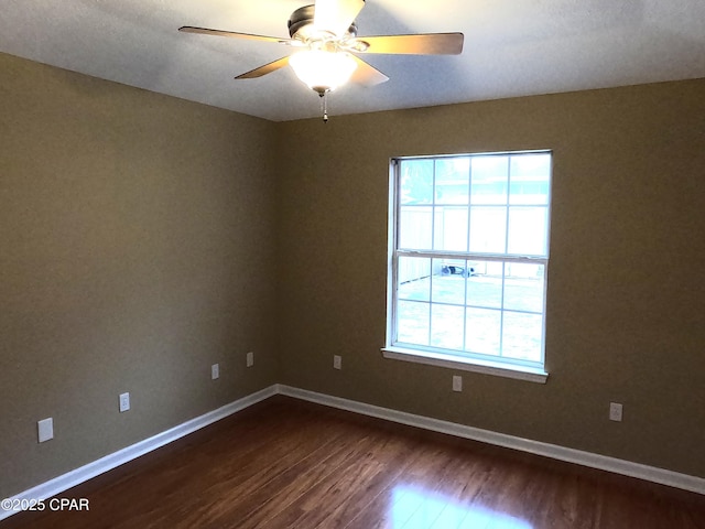 spare room featuring dark wood-type flooring and ceiling fan