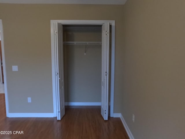 unfurnished bedroom featuring a closet and dark wood-type flooring