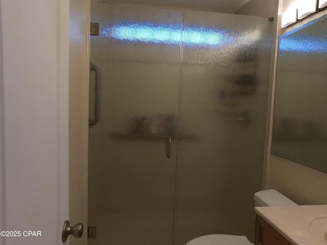 bathroom with walk in shower, vanity, and toilet