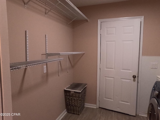 walk in closet with washer / dryer and light hardwood / wood-style floors