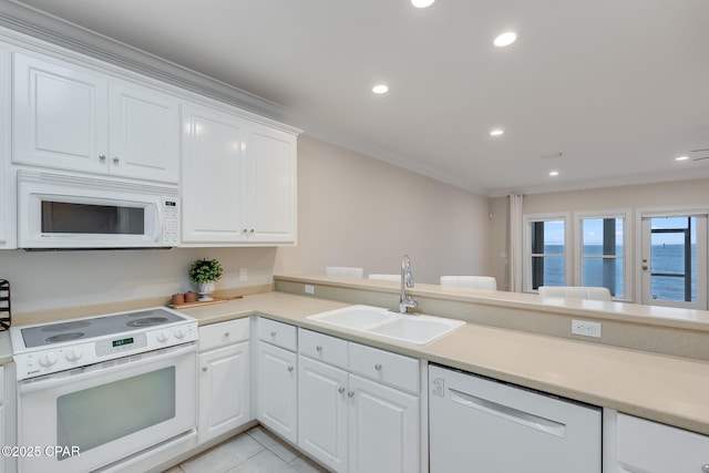 kitchen with kitchen peninsula, white appliances, sink, a water view, and white cabinets