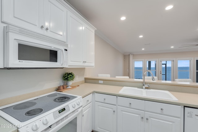 kitchen featuring sink, white appliances, white cabinets, and a water view