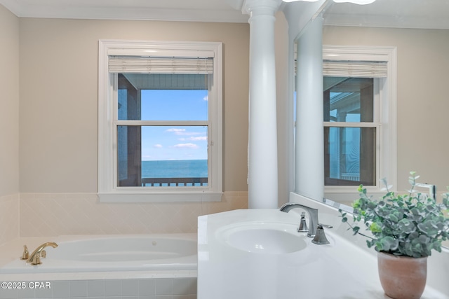 bathroom with a water view, vanity, a relaxing tiled tub, and decorative columns