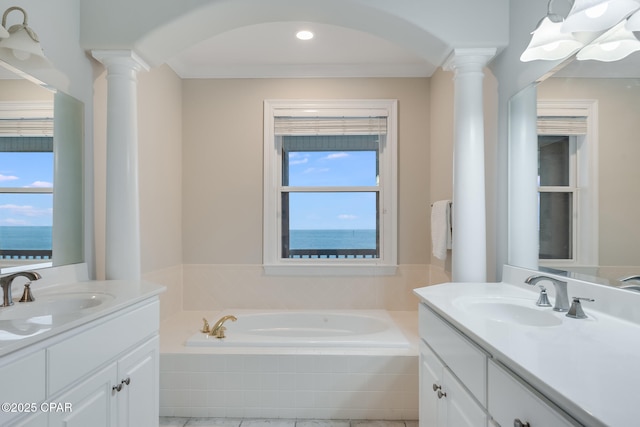 bathroom with a water view, vanity, tiled tub, and ornate columns