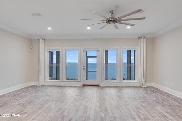 empty room featuring ceiling fan, a water view, crown molding, and light hardwood / wood-style flooring