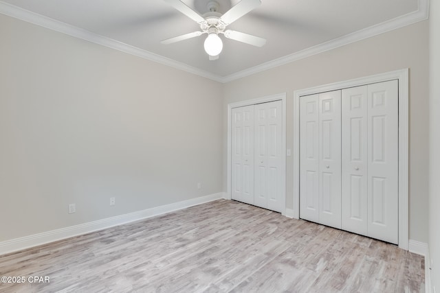 unfurnished bedroom with ceiling fan, light wood-type flooring, ornamental molding, and multiple closets