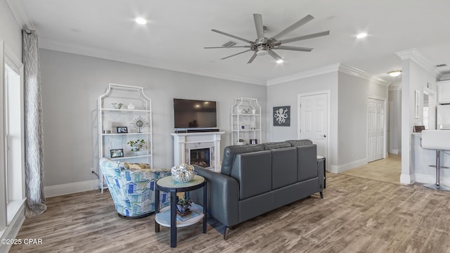 living room with ceiling fan, ornamental molding, and light hardwood / wood-style floors