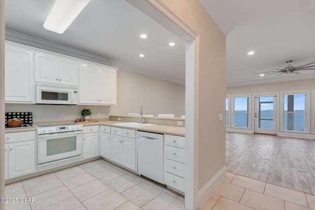 kitchen with white appliances, crown molding, sink, a water view, and white cabinets