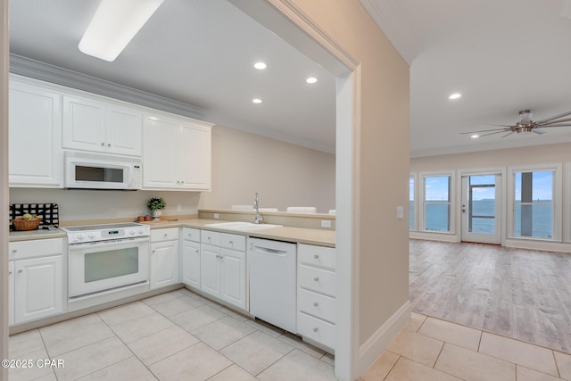 kitchen with sink, white appliances, light tile patterned floors, white cabinetry, and a water view