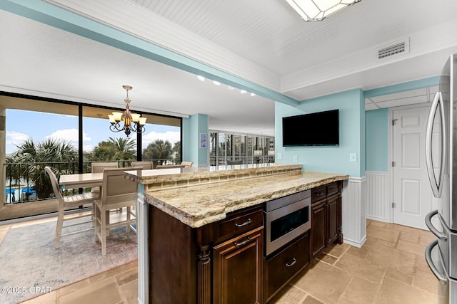 kitchen featuring stainless steel appliances, kitchen peninsula, dark brown cabinets, a chandelier, and pendant lighting