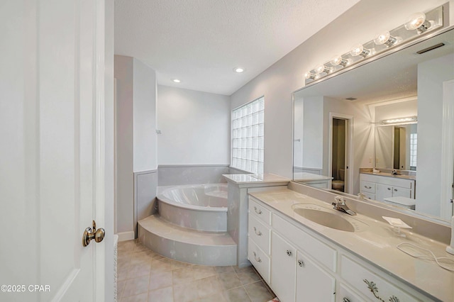 bathroom featuring vanity, a bath, tile patterned floors, and a textured ceiling