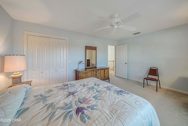 bedroom featuring light colored carpet, ceiling fan, and a closet