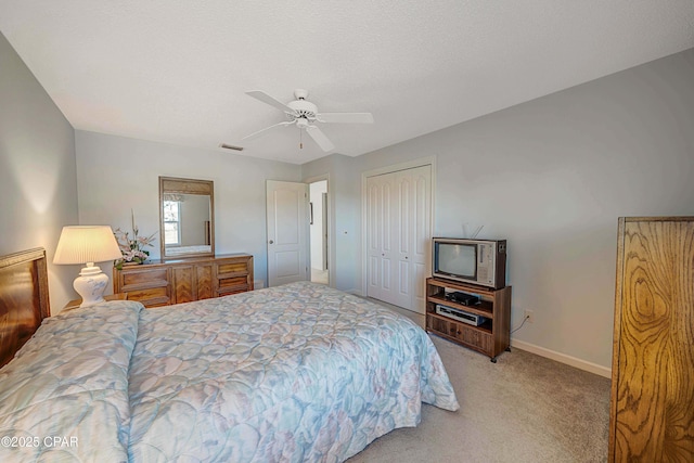 carpeted bedroom with ceiling fan, a closet, and a textured ceiling