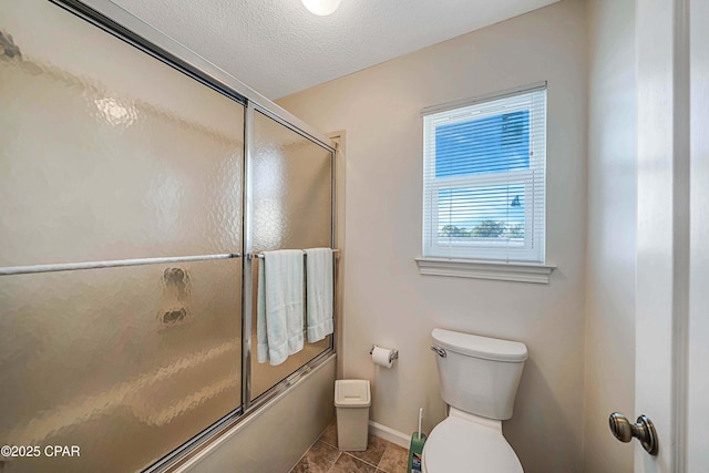 bathroom with bath / shower combo with glass door, toilet, and a textured ceiling