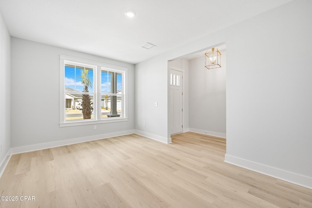 spare room featuring an inviting chandelier and light hardwood / wood-style flooring