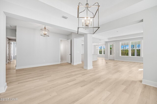 unfurnished living room featuring a chandelier and light wood-type flooring