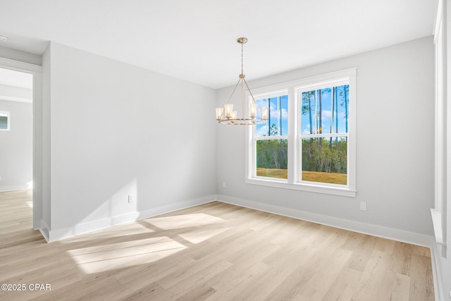 unfurnished room featuring an inviting chandelier and light hardwood / wood-style floors