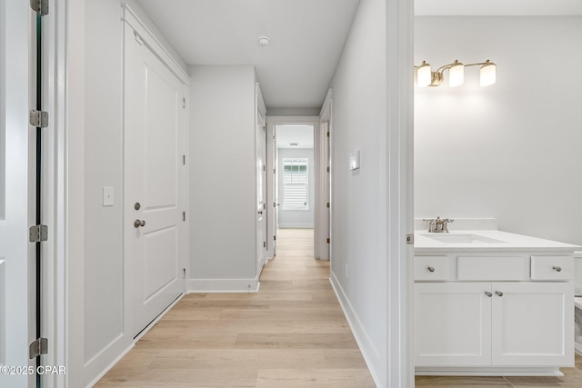 hallway with sink and light hardwood / wood-style flooring