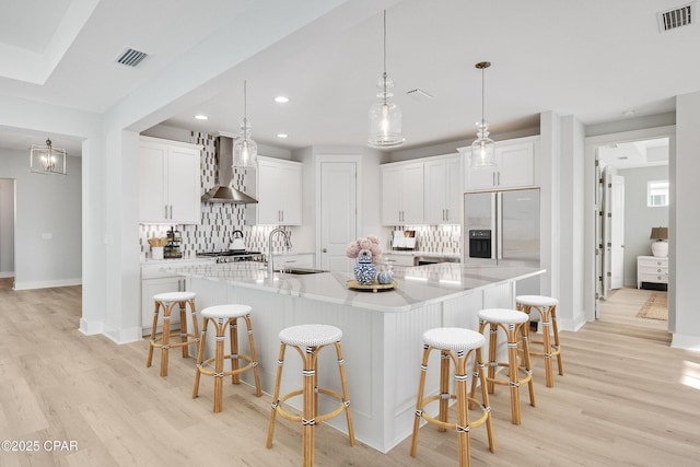 kitchen with white cabinetry, wall chimney exhaust hood, and a large island