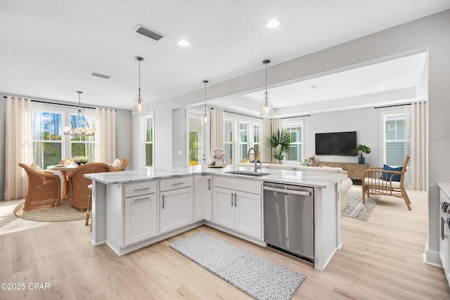 kitchen with sink, dishwasher, white cabinetry, hanging light fixtures, and light stone countertops