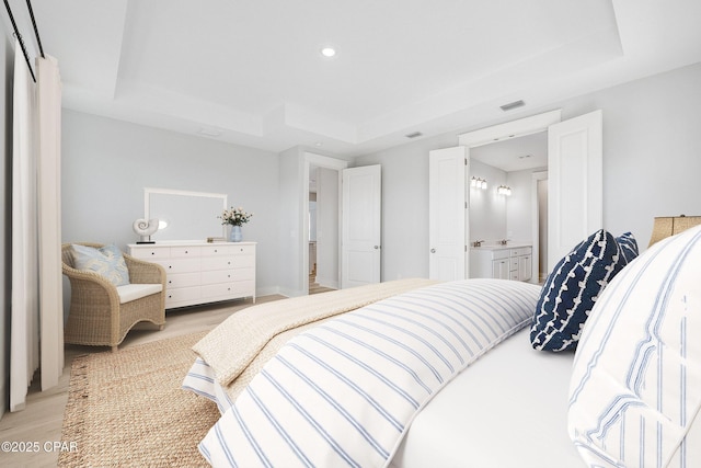 bedroom with a raised ceiling and light wood-type flooring