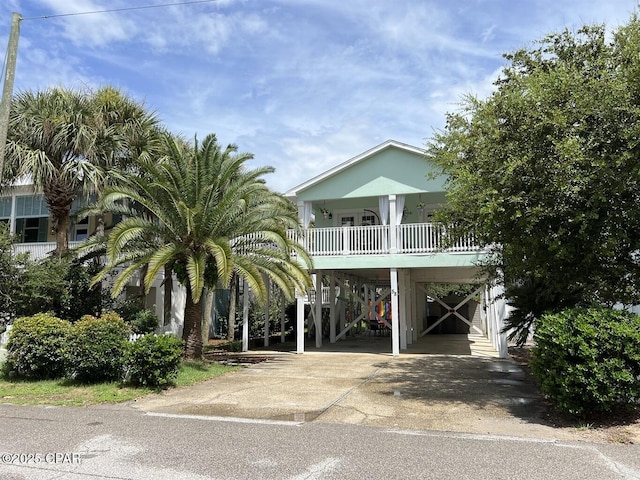 view of front facade with stairs, a carport, a porch, and concrete driveway