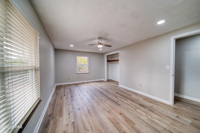 unfurnished bedroom featuring ceiling fan, light hardwood / wood-style floors, a textured ceiling, and a closet