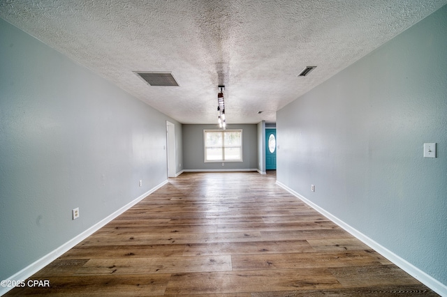 empty room with hardwood / wood-style floors and a textured ceiling