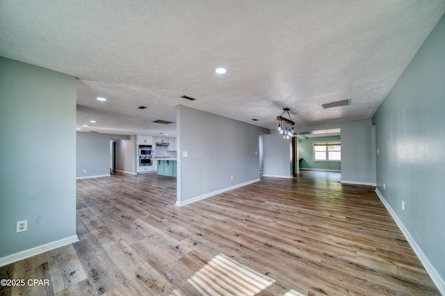 unfurnished living room featuring a textured ceiling and light wood-type flooring