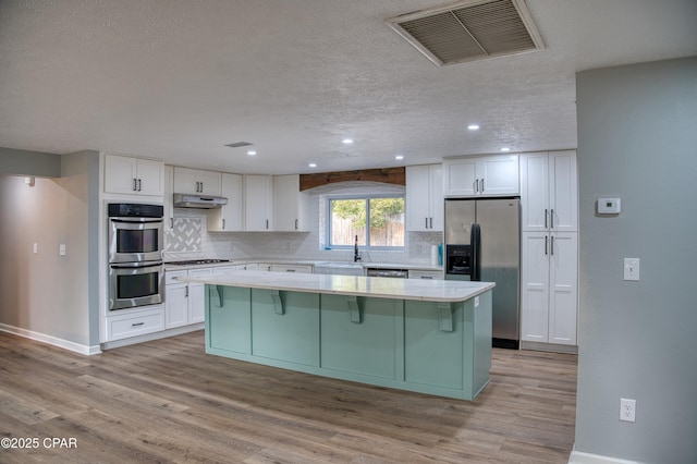 kitchen featuring appliances with stainless steel finishes, decorative backsplash, white cabinets, and a center island