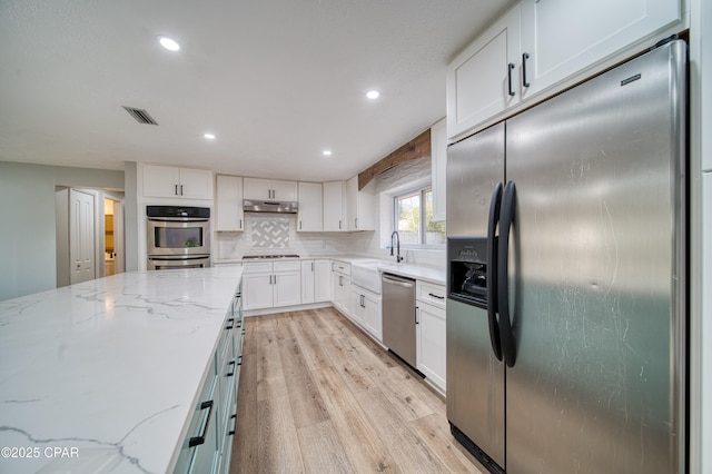 kitchen featuring appliances with stainless steel finishes, light stone counters, and white cabinetry