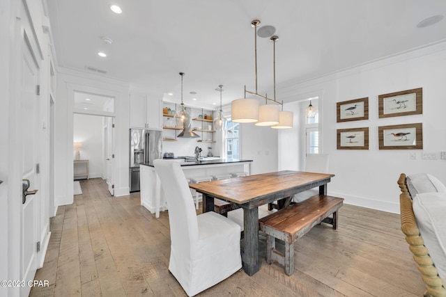 dining area featuring light wood-type flooring and ornamental molding