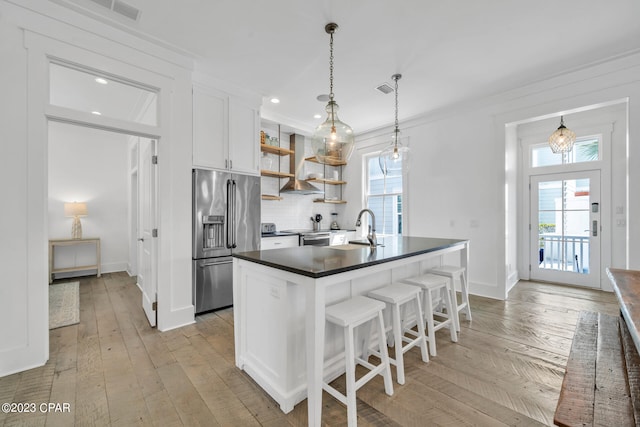 kitchen featuring light hardwood / wood-style flooring, island range hood, stainless steel appliances, a breakfast bar area, and white cabinetry