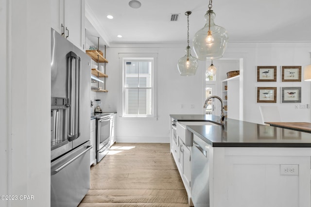 kitchen with stainless steel appliances, sink, white cabinetry, ornamental molding, and hanging light fixtures