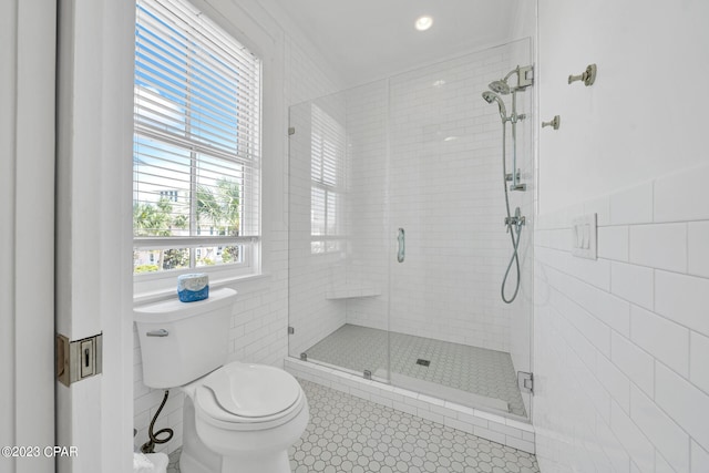 bathroom with toilet, a shower with door, tile walls, and tile patterned floors