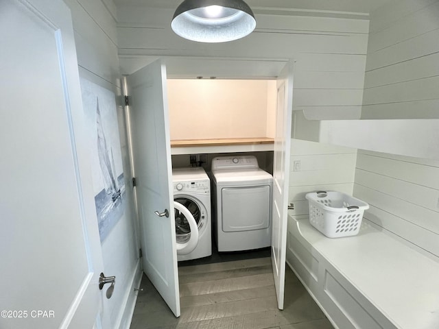 washroom with independent washer and dryer, wooden walls, and wood-type flooring