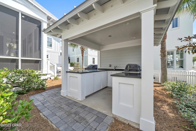 view of patio / terrace featuring exterior kitchen, a sunroom, and a grill