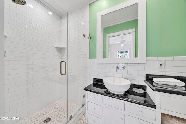 bathroom featuring vanity, ceiling fan, ornamental molding, a shower with shower door, and tasteful backsplash