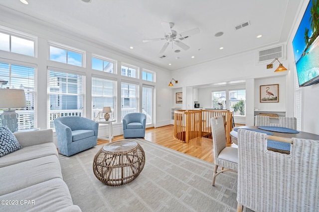 living room with ceiling fan, crown molding, and light hardwood / wood-style flooring