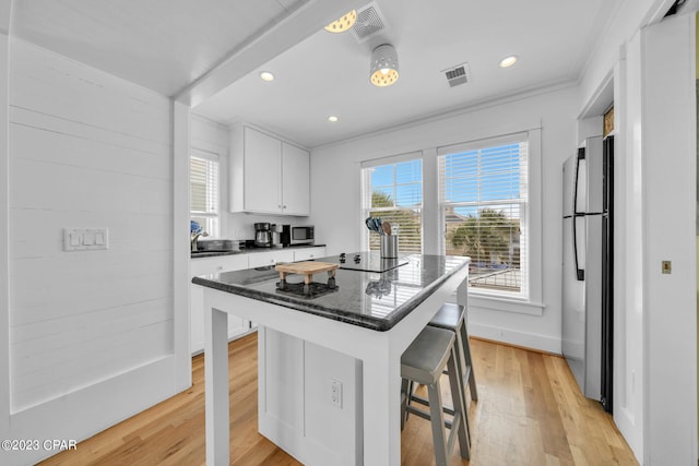 kitchen featuring a center island, light wood-type flooring, a breakfast bar area, white cabinets, and appliances with stainless steel finishes