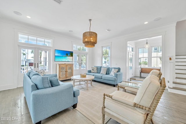 living room with french doors, ornamental molding, a wealth of natural light, and light hardwood / wood-style floors