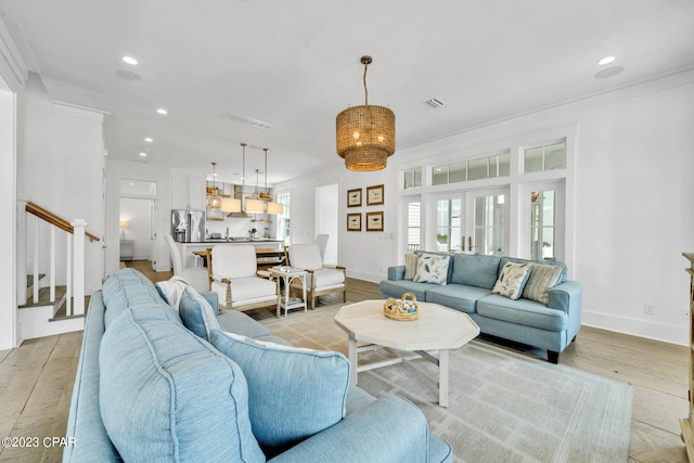 living room featuring french doors, ornamental molding, and light hardwood / wood-style floors