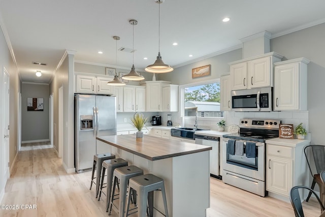 kitchen with a center island, backsplash, white cabinets, appliances with stainless steel finishes, and sink