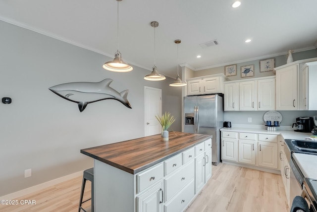 kitchen with a kitchen island, stainless steel fridge with ice dispenser, wood counters, and white cabinetry